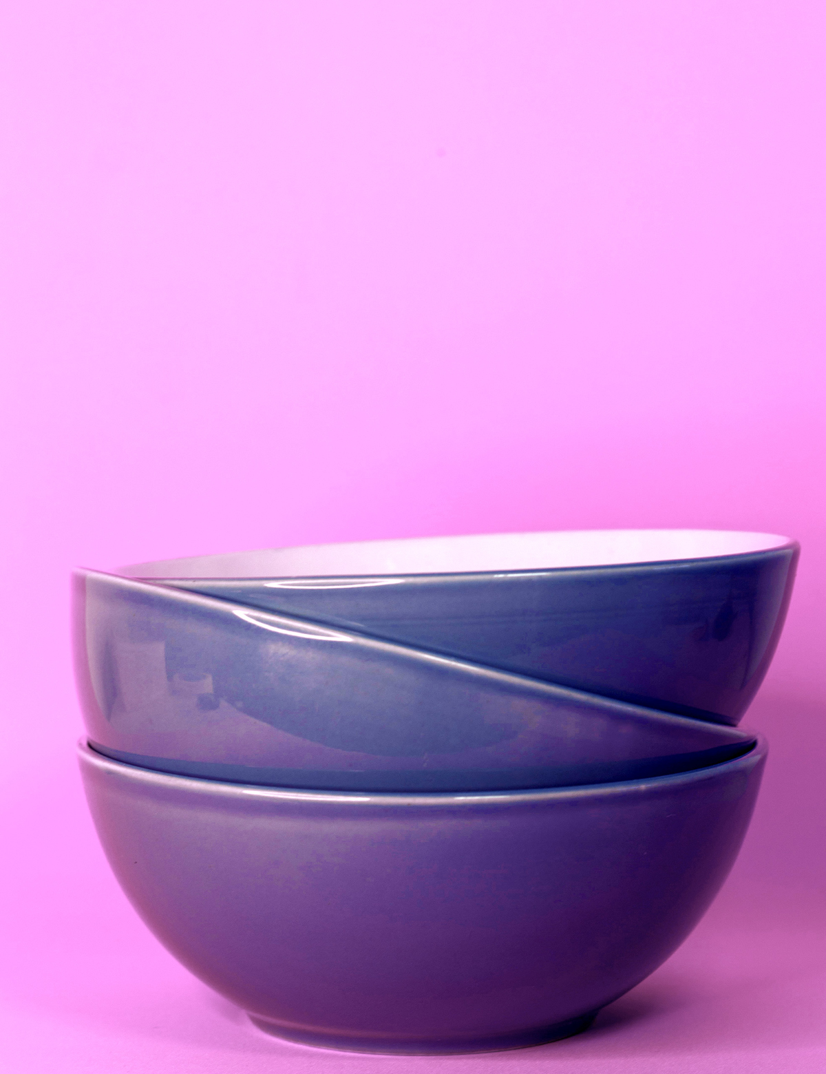 Three blue bowls stacked on a pink table